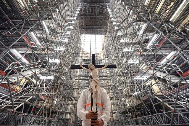 A catholic faithful holds a crucifix during a prayer carried out by prelates in the Notre-Dame cathedral in Paris on April 15, 2022, to mark the third anniversary of a fire that partially destroyed the cathedral. (Photo by Bertrand Guay/AFP Photo)