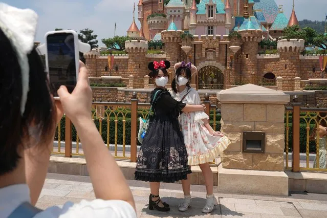 Visitors wearing face masks take photos at the Hong Kong Disneyland, Thursday, April 21, 2022. Hong Kong Disneyland reopened to the public after shutting down due to a surge in COVID-19 infections. (Photo by Kin Cheung/AP Photo)