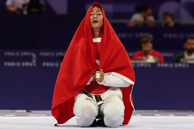 Turkey's Nafia Kus Aydin celebrates with her country's flag after winning against Britain's Rebecca Mcgowan in the taekwondo women's +67kg bronze medal bout of the Paris 2024 Olympic Games at the Grand Palais in Paris on August 10, 2024. (Photo by David Gray/AFP Photo)