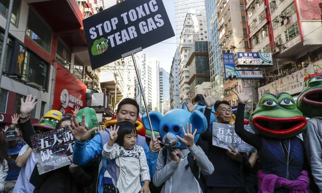 Masked pro-democracy protesters wave as they march on a street in Hong Kong, Sunday, December 8, 2019. Marchers are again expected to fill Hong Kong streets Sunday in a rally that will test the enduring appeal of an anti-government movement marking a half year of demonstrations. (Photo by Mark Schiefelbein/AP Photo)