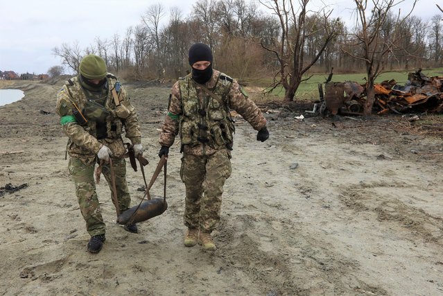 Military sappers carry an unexploded shell left after Russia's invasion near the village of Motyzhyn, in Kyiv region, Ukraine on April 10, 2022. (Photo by Mykola Tymchenko/Reuters)