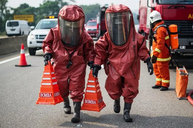 Members of a Malaysian hazardous disaster emergency response team wearing protective suits take part in a trasportation emergency response drill “Ex-Eagle” on a highway near Bentong, outside Kuala Lumpur on June 24, 2014. The drill ensures transportation emergency incidents are managed in an effective and efficient manner. (Photo by Mohd Rasfan/AFP Photo)