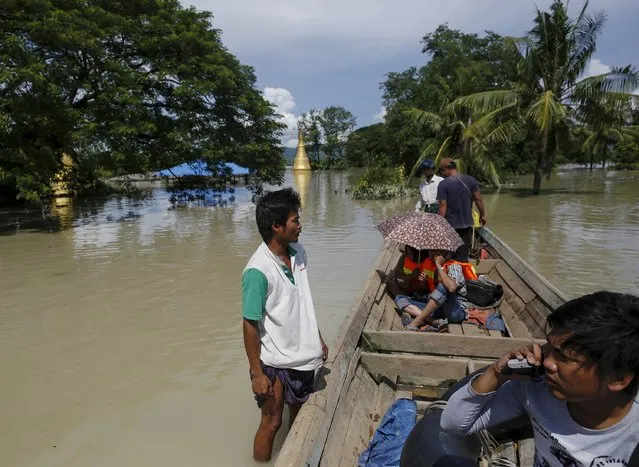 A boat man (L) stands on the flooded roof of a home next to the media boat in a flooded village at Kalay township at Sagaing division, August 2, 2015. Storms and floods have so far killed 21 people, with water levels as high as 2.5 metres in Sagaing and 4.5 metres in western Rakhine state, according to the government, which on Friday declared four regions disaster zones. (Photo by Soe Zeya Tun/Reuters)