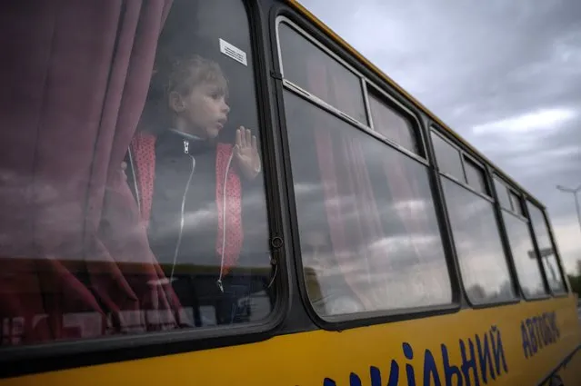 A girl looks out from a bus as families from Russian occupied territories in the Zaporizhzhia region arrive in a humanitarian convoy at a registration and processing centre for internally displaced people in Zaporizhzhia on April 29, 2022, amid Russia's military invasion launched on Ukraine. (Photo by Ed Jones/AFP Photo)