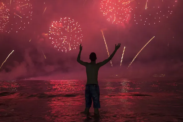 A man watches fireworks exploding over Copacabana Beach during the New Year's celebrations, in Rio de Janeiro, Brazil, Wednesday, January 1, 2020. (Photo by Bruna Prado/AP Photo)