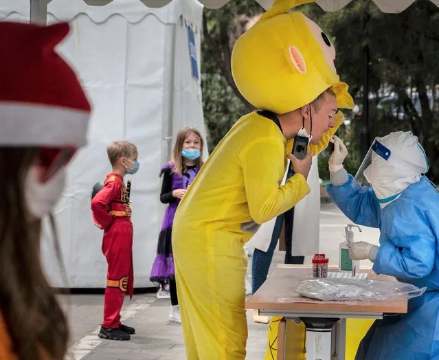 A foreign resident wears a costume as a health worker gives him a nucleic acid test to detect COVID-19 at a testing site on May 10, 2022, in an effort to cheer family and others up, in Beijing, China. China is trying to contain a spike in coronavirus cases in the capital Beijing after hundreds of people tested positive for the virus in recent weeks, causing local authorities to initiate mass testing in most districts, close schools and stores, ban gatherings and inside dining in all restaurants, and to lockdown some neighbourhoods in an effort to maintain the country's zero COVID strategy.(Photo by Kevin Frayer/Getty Images)