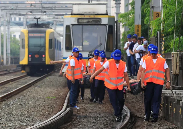 Rescuers carry mock victims acting as commuters of the Light Rail Transit (LRT) while crossing the train tracks during a metrowide simultaneous earthquake drill in metro Manila, Philippines June 22, 2016. (Photo by Romeo Ranoco/Reuters)