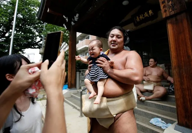 Sumo wrestler Kyokutaisei poses for a photograph with a baby after their training session in Nagoya, Japan on July 18, 2017. (Photo by Issei Kato/Reuters)