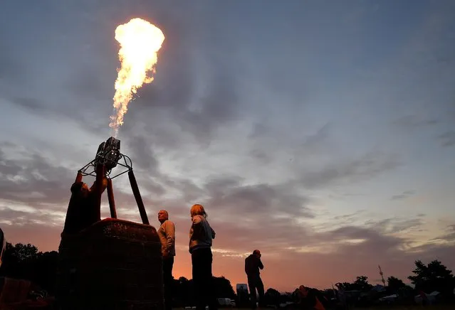 A crew tests a burner as balloons launch during a mass take off at the annual Bristol hot air balloon festival in Bristol, Britain, August 8, 2019. (Photo by Toby Melville/Reuters)