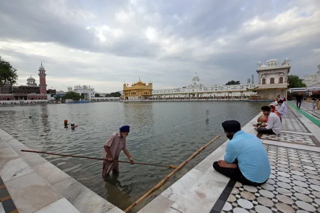 A Sikh volunteer cleans the Sarowar or the sacred pond of the Golden Temple, the holiest of Sikh shrines, in Amritsar, India, 24 July 2017. Throughout the year, tourists and pilgrims visit to pay obeisance at the Golden Temple, the most sacred pilgrimage center for the Sikhs all over the world. (Photo by Raminder Pal Singh/EPA/EFE)