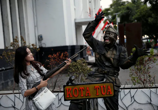 A tourist poses for a take picture with a street performer dressed as an Indonesian soldier in Jakarta's Old Town compound, a popular tourist spot in Jakarta, Indonesia August 2, 2017. (Photo by Reuters/Beawiharta)