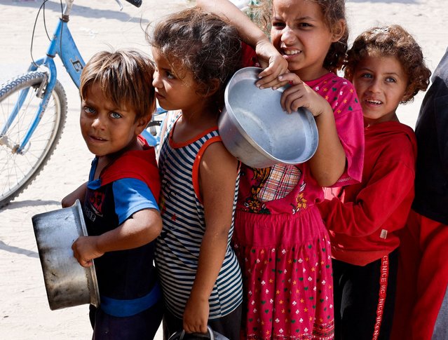 Palestinian children queue to receive food cooked by a charity kitchen, amid the Israel-Hamas conflict, in Khan Younis in the southern Gaza Strip on October 16, 2024. (Photo by Mohammed Salem/Reuters)