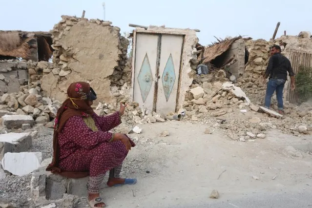 A woman (L) sits outside the rubble of her house in the aftermath of a powerful earthquake, in Sayeh Khosh village, Hormozgan province, southern Iran, 02 July 2022. At least five people were killed when a 6.1-magnitude earthquake hit southern Iran in the early hours of 02 July. The main quake was followed by two powerful aftershocks of up to 6.3 magnitude, the Iranian Red Crescent Society said. (Photo by Abdol Hossein Rezvani/EPA/EFE)