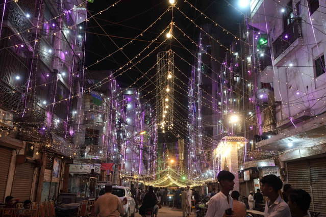 People walks through a street decorated with lights for the upcoming Mawlid al-Nabi holiday celebrating the birthday of Islam's prophet, Muhammad, born in the year 570, in Karachi, Pakistan, Friday, September 13, 2024. (Photo by Fareed Khan/AP Photo)