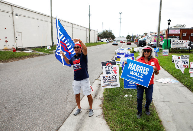 Robert Browning (L) and Terri Bieberbach wave campaign sings outside of a polling precinct on Election Day at the Town 'N Country Regional Public Library in Tampa, Florida, U.S., November 5, 2024. (Photo by Octavio Jones/Reuters)