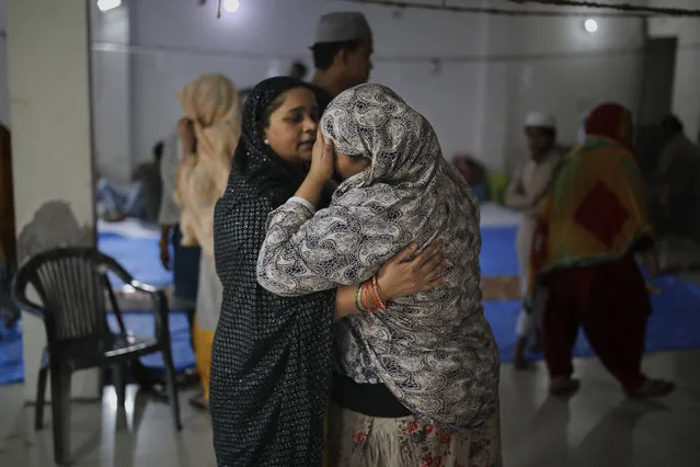 In this Friday, February 28, 2020 photo, a woman comforts a neighbor inside a hall at Al-Hind hospital used as a shelter for people who were rescued after they were attacked by a Hindu mob, in Old Mustafabad neighborhood of New Delhi, India. On the eve of U.S. President Donald Trump’s first state visit to India last Sunday, Hindus and Muslims in the Indian capital charged at each other with homemade guns and crude weapons, leaving the streets where the rioting occurred resembling a war zone, with houses, shops, mosques, schools and vehicles up in flames, more than 40 dead and hundreds injured. (Photo by Altaf Qadri/AP Photo)