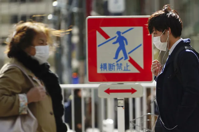 Pedestrians with protective masks on a street Thursday, March 5, 2020, in Tokyo. The number of infections of the COVID-19 disease spread around the globe. (Photo by Eugene Hoshiko/AP Photo)