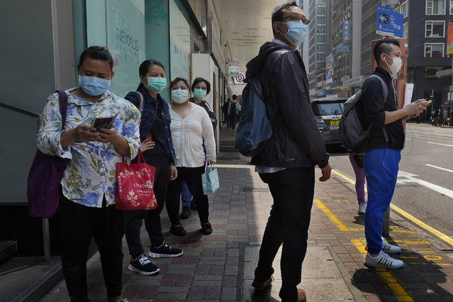 People wearing face masks walk at a down town street in Hong Kong Monday, March 16, 2020. For most, the coronavirus causes only mild or moderate symptoms, such as fever and cough. But for a few, especially older adults and people with existing health problems, it can cause more severe illnesses, including pneumonia. (Photo by Vincent Yu/AP Photo)