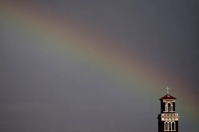 The steeple at Our Lady of Sorrows Catholic Church stands against a rainbow as light showers moved through Kansas City, Mo., Thursday, April 21, 2022. (Photo by Charlie Riedel/AP Photo)