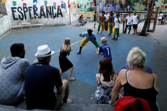 A member of the Acorda Capoeira (Awaken Capoeira) group teaches capoeira to two foreign visitors in the Rocinha favela in Rio de Janeiro, Brazil, July 26, 2016. (Photo by Bruno Kelly/Reuters)