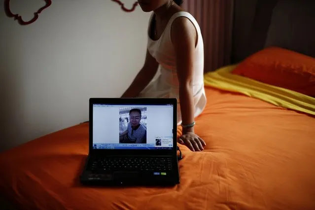 Liu, whose husband Lu was onboard Malaysia Airlines Flight MH370 which disappeared on March 8, 2014, shows her husband's picture on his laptop during an interview with Reuters in Beijing July 18, 2014, shows her husband's picture on his laptop as she sits on a bed they shared together at her home. (Photo by Kim Kyung-Hoon/Reuters)