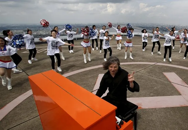 German musician Stefan Aaron plays the piano as cheerleaders perform next to him on top of the Yokohama Landmark Tower, which is 296m high and is the second tallest building in Japan, as part of his Orange Piano Tour in Yokohama, south of Tokyo, Japan September 4, 2015. (Photo by Yuya Shino/Reuters)