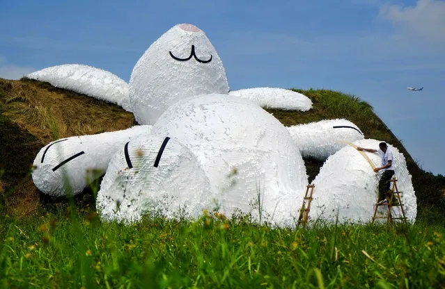 Dutch artist Florentijn Hofman's latest creation, a 25 meters (82 feets) white rabbit, leans up against an old aircraft hangar as part of the Taoyuan Land Art Festival in Taoyuan, Taiwan, Tuesday, September 2, 2014. (Photo by Wally Santana/AP Photo)