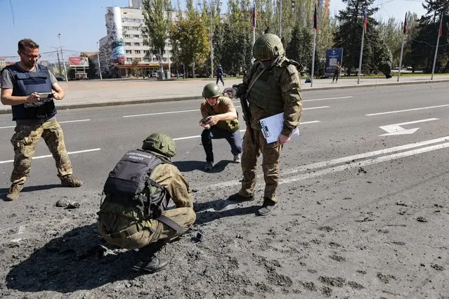 Investigators work at the site of a burning vehicle after shelling in Donetsk, area controlled by Russian-backed separatist forces, eastern Ukraine, Saturday, September 17, 2022. A Ukrainian shelling attack killed four people in downtown Donetsk on Saturday. According to the city's Mayor Alexey Kulemzin, fragments of munitions for Caesar howitzers were found. (Photo by Alexei Alexandrov/AP Photo)