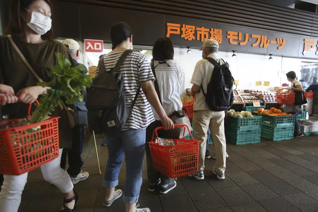 People wearing face masks to protect against the spread of the new coronavirus enjoy shopping at a fruit and vegetable shop in Yokohama, near Tokyo, Tuesday May 12, 2020. (Photo by Koji Sasahara/AP Photo)