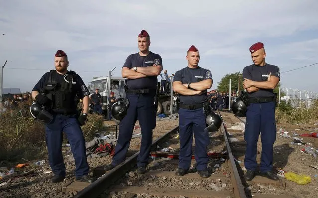 Hungarian police officers stand in front of a fence on the Serbian side of the border after sealing it near the village of Horgos, Serbia, September 14, 2015, near the Hungarian migrant collection point in Roszke. (Photo by Marko Djurica/Reuters)