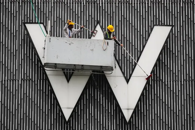 Workers clean the “W” signboard at the W Hotel in Kuala Lumpur, Malaysia, 03 September 2022. (Photo by Fazry Ismail/EPA/EFE)