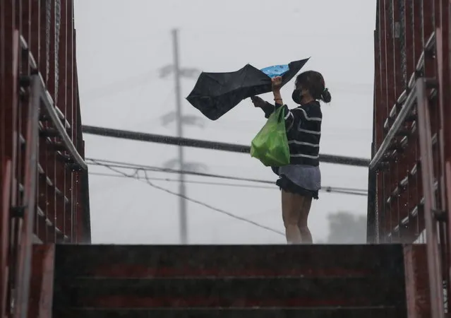 A woman struggles to hold her umbrella amidst gusts of wind at a crossing bridge in Quezon City, Metro Manila, Philippines, 29 October 2022. Data from the National Disaster Risk Reduction and Management Council (NDRRMC) showed that 45 people died from the effects of Typhoon Nalgae as of 29 October. Tracking by the country’s weather bureau places the typhoon in the southern Luzon region moving in a west southwestward direction. (Photo by Rolex Dela Pena/EPA/EFE)