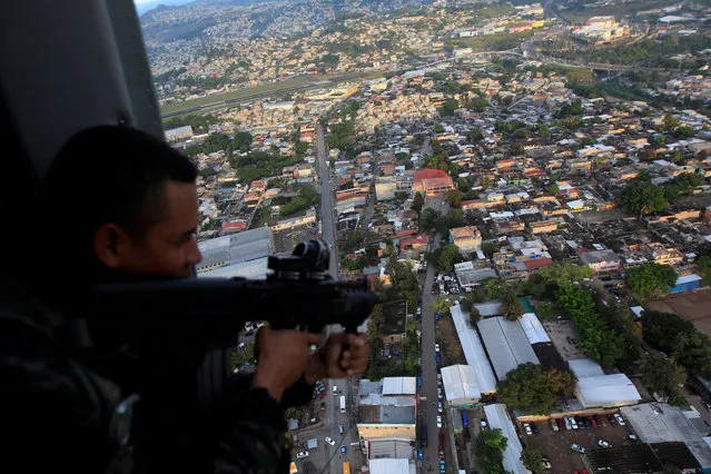 A soldier in a military helicopter aims his weapon during a patrol of the operation “Peace and Democracy II” as part of the security measures for the November 26 presidential election, in Tegucigalpa, Honduras on November 23, 2017. (Photo by Jorge Cabrera/Reuters)