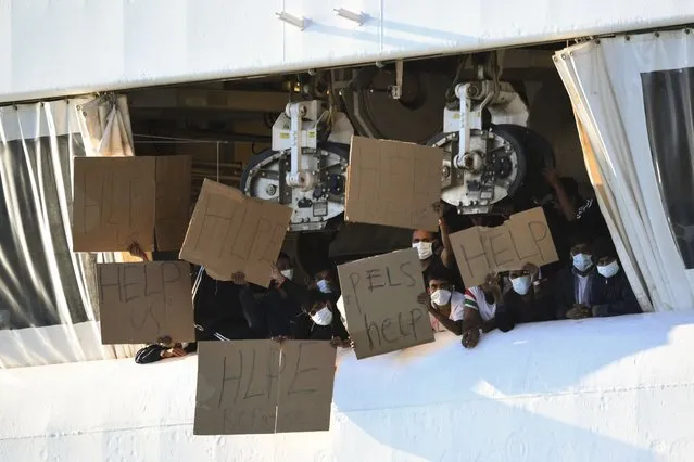 Migrants hold banners asking for help, from a deck of the Norway-flagged Geo Barents ship operated by Doctors Without Borders, in Catania's port, Sicily, southern Italy, Monday, October 7, 2022. The Geo Barents has been allowed Sunday to disembark 357 migrant that Italian authorities defined as “vulnerable people” and minors, while leaving another 215 people that were declared non-vulnerable blocked on board. (Photo by Salvatore Cavalli/AP Photo)