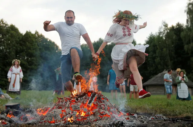 People jump over a campfire as they take part in the Ivan Kupala festival in Belarusian state museum of folk architecture and rural lifestyle near the village Aziarco, Belarus, July 4, 2020. (Photo by Vasily Fedosenko/Reuters)