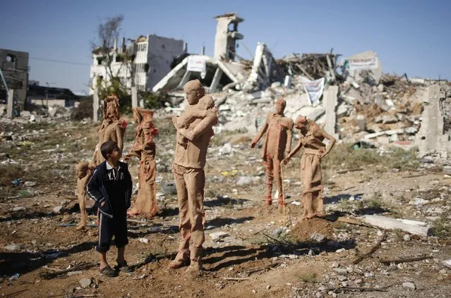 A Palestinian boy looks at statues that are made of fiberglass and covered with clay by Palestinian artist Eyad Sabbah, which are depictions for the Palestinians who fled their houses from Israeli shelling during the most recent conflict between Israel and Hamas, in the east of Gaza City October 21, 2014. (Photo by Mohammed Salem/Reuters)