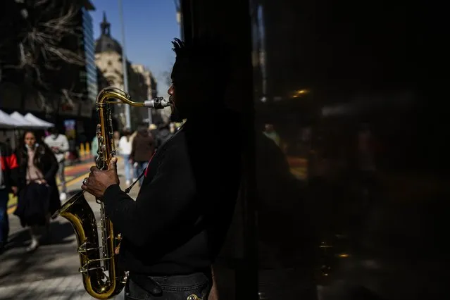 Haitian migrant Philippe Sax, plays his saxophone for alms in downtown Santiago, Chile, Friday, August 19, 2022. (Photo by Esteban Felix/AP Photo)