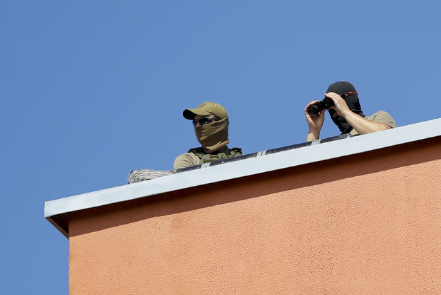Belarusian Interior Ministry soldiers watch from a ruff as friends and relatives of those detained during mass rally following presidential election gather at a detention center in Minsk, Belarus, Tuesday, August 11, 2020. (Photo by Sergei Grits/AP Photo)