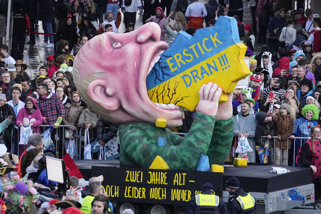 A carnival float depicts Russia's president Vladimir Putin eating Ukraine, lettering reads "choke on it" during the traditional carnival parade in Duesseldorf, Germany, on Monday, February 12, 2024. The foolish street spectacles in the carnival centers of Duesseldorf, Mainz and Cologne, watched by hundreds of thousands of people, are the highlights in Germany's carnival season on Rosemonday. (Photo by Martin Meissner/AP Photo)