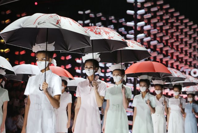 Models wearing masks hold umbrellas as they perform during the TORAY Liu Wei Collection segment at China Fashion Week in Beijing, October 30, 2014. (Photo by Jason Lee/Reuters)