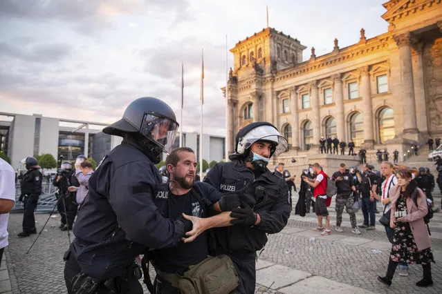 Police officers push away a crowd of demonstrators from the square “Platz der Republik” in front of the Reichstag building during a demonstration against the Corona measures in Berlin, Germany, Saturday, August 29, 2020. (Photo by Christoph Soeder/dpa via AP Photo)