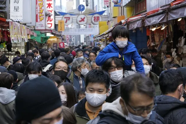 People wearing face masks flock to a shopping street famous for a year-end shopping before New Year holidays in Tokyo, Friday, December 30, 2022. Japan on Friday started requiring COVID-19 tests for all passengers arriving from China as an emergency measure against surging infections there and as Japan faces rising case numbers and record-level deaths at home. (Photo by Hiro Komae/AP Photo)