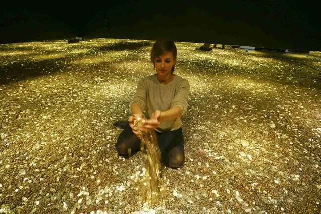 Sonja Enz of the Stapferhaus, an event place for contemporary exhibitions, holds coins in her hands as she sits in a room filled with 4 million Swiss five cent coins during a media preview of the exhibition “Geld – Jenseits von Gut und Boese” (Money – beyond good and evil) in the town of Lenzburg west of Zurich November 14, 2014. The exhibition at the Stapferhaus is opened to the public from November 15 to November 29, 2015. (Photo by Arnd Wiegmann/Reuters)