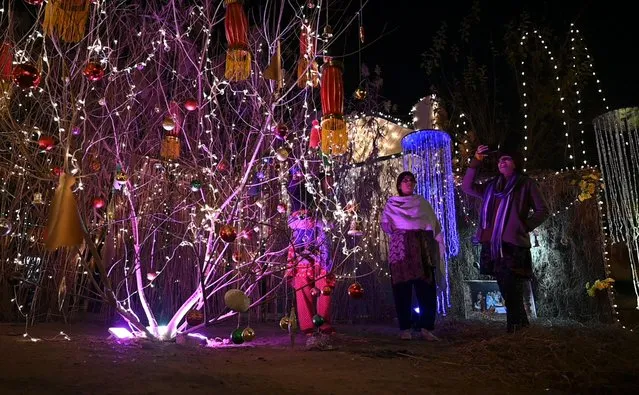 People celebrate Christmas eve along an illuminated street in Islamabad on December 24, 2022. (Photo by Farooq Naeem/AFP Photo)