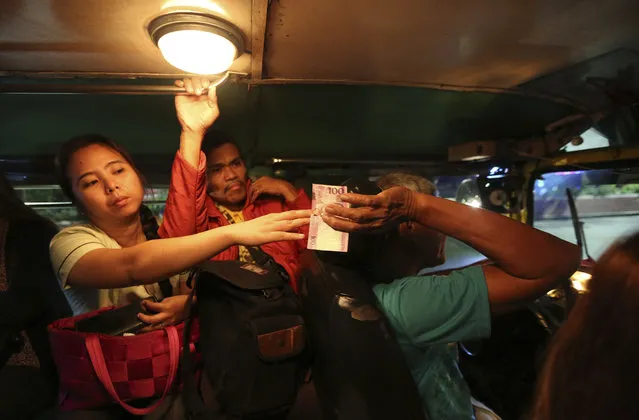 In this September 26, 2017, photo, a passenger passes her jeepney fare to driver Victorino Samson, 62, in Manila, Philippines. Samson has supported his family with his earnings as a jeepney driver for 30 years. A Philippine government modernization program aims a major makeover of the jeepney and other modes of public transport by improving their engines, safety and convenience. (Photo by Aaron Favila/AP Photo)