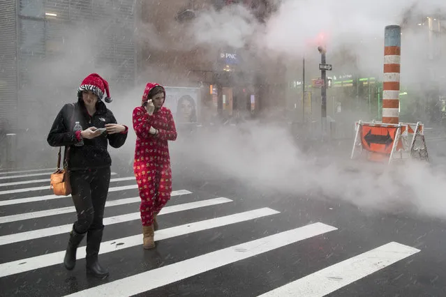 Snow falls on a couple of Santa Con revelers as they bar hop in lower Manhattan, Saturday, December 9, 2017, in New York. (Photo by Mary Altaffer/AP Photo)