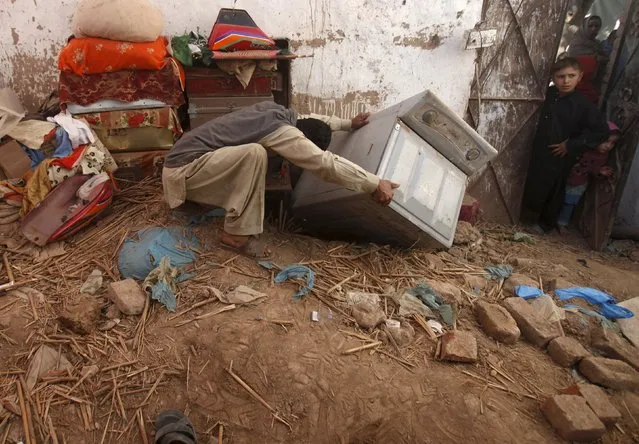 A man retrieves a washing machine stuck in the rubble after a roof collapsed during the aftershocks following Monday's earthquake, in Peshawar, Pakistan October 28, 2015. A powerful earthquake struck a remote area of northeastern Afghanistan on Monday, shaking the capital Kabul, as shockwaves were felt in northern India and in Pakistan's capital, where hundreds of people ran out of buildings as the ground rolled beneath them. (Photo by Fayaz Aziz/Reuters)