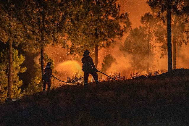 This handout photo released by the Military Emergency Unit (UME) on July 31, 2025, shows firefighters battling a wildfire near Caminomorisco, Extremadura region, western Spain. Firefighters battle a wildfire on the ground and in the air in the Spanish province of Avila and in the region of Extremadura. (Photo by Handout/UME via AFP Photo)