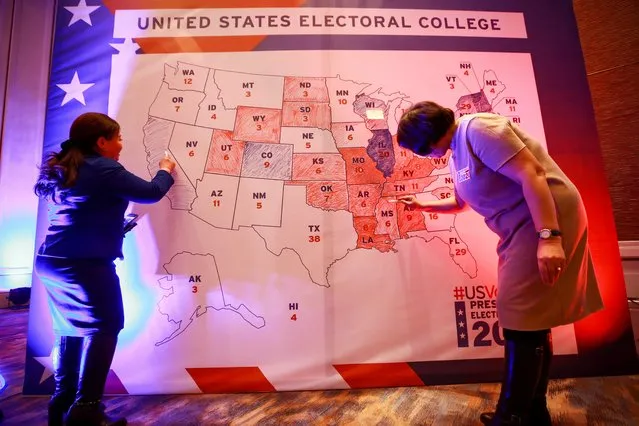 People colour in an electoral map during a US presidential election watch party at the US embassy in Ulaanbaatar, the capital of Mongolia on November 4, 2020. (Photo by Byambasuren Byamba-Ochir/AFP Photo)