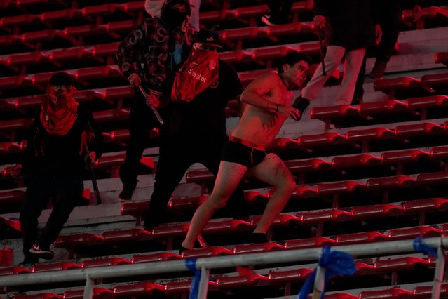 Fans of Argentina's Independiente attack a Universidad de Chile fan, right, after they stripped him of his clothing during a Copa Sudamericana round of sixteen second leg soccer match at the Libertadores de America stadium in Avellaneda, Argentina, Wednesday, August 20, 2025. (Photo by Gustavo Garello/AP Photo)